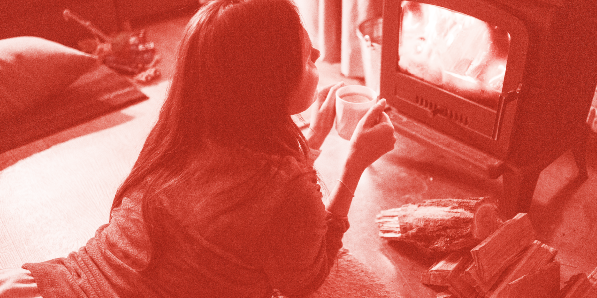 Woman in front of the fire at home keeping warm
